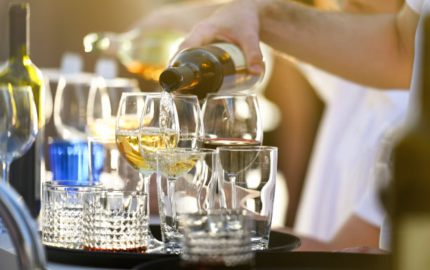 酒保正在往玻璃杯里倒白葡萄酒图片下载