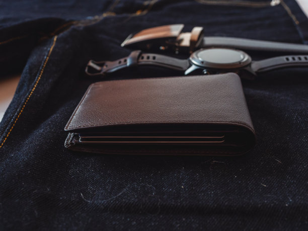 棕色皮革钱包上的牛仔裤背景。图片下载