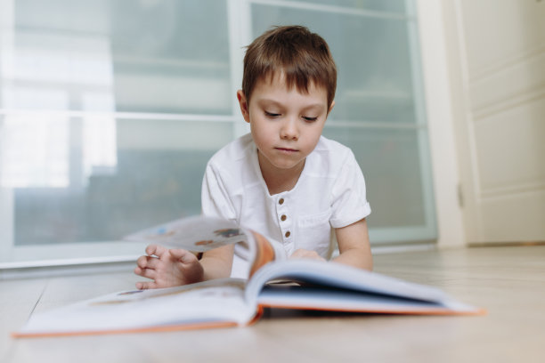 一个男孩在家里的地板上看书。选择性聚焦图像图片下载