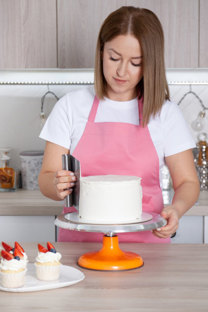 糕点师，糖果师厨房里的年轻白人女性。她正在架子上装饰蛋糕图片下载