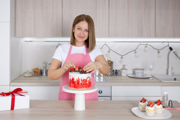 糕点师，糖果师厨房里的年轻白人女性。她正在架子上装饰蛋糕图片下载