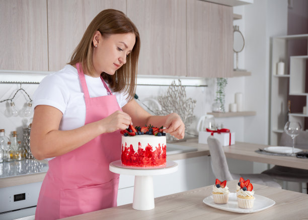 糕点师，糖果师厨房里的年轻白人女性。她正在架子上装饰蛋糕图片下载