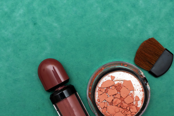 绿色背景上隔离的破损腮红、口红和刷子图片下载