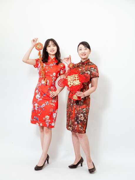 亚洲妇女都穿着传统的旗袍旗袍举行中国的节日对联庆祝新年，在白色的背景上有“愿年年有余”的意思。图片下载