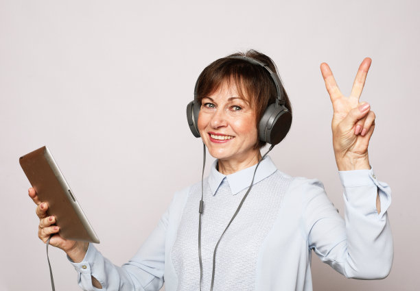 生活方式、技术和人的概念:一位老年妇女获得了一个新的职业使用平板电脑。听学习。图片下载