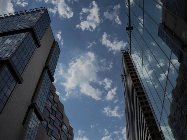 天空和建筑的玻璃立面。蓝天白云在玻璃墙上的倒影。城市摩天大楼。现代玻璃建筑和建筑。生态的概念图片下载