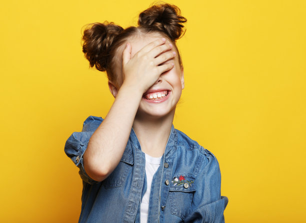 小女孩笑着用手掌闭上了眼睛图片下载