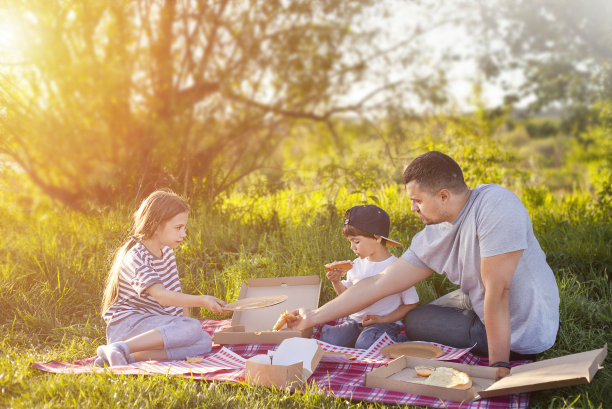 父亲和两个孩子坐在户外野餐图片下载