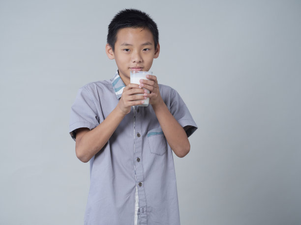 灰色背景的小男孩在喝牛奶图片下载