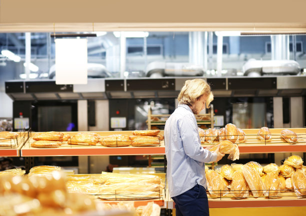 一个男人在超市里挑选面包图片下载