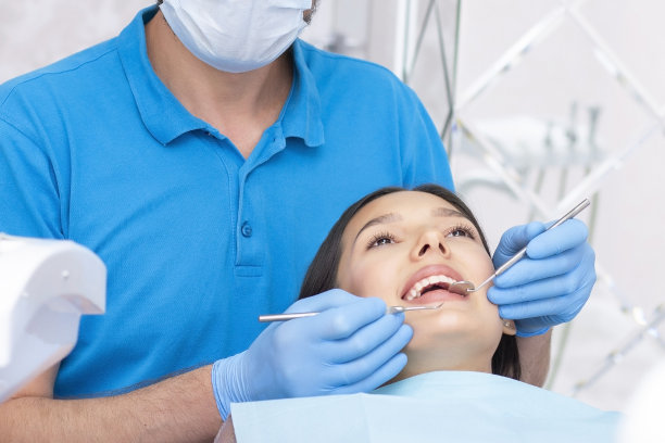 迷人的年轻女子在牙科诊所与一名男牙医。健康的牙齿的概念。图片下载