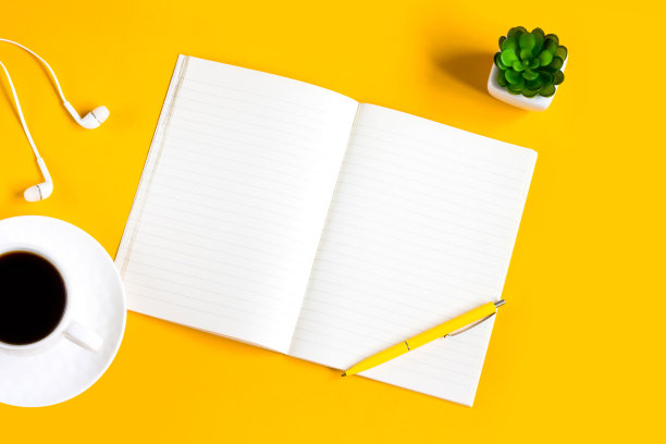 笔记本，手机，植物，钢笔，耳机在一个黄色的背景上的拷贝空间，平铺。俯视图图片下载