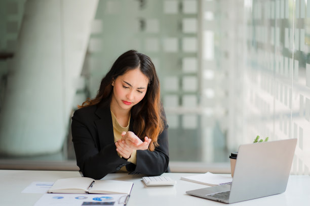 一位女会计长时间使用电脑后手腕疼痛。在办公桌上使用笔记本电脑会感到疼痛图片下载