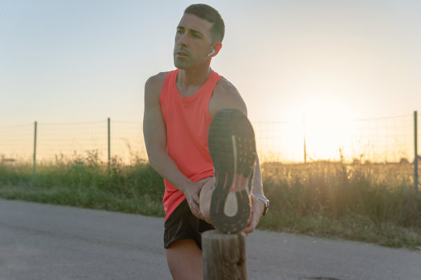 年轻的跑步者在木桩上放松一条腿。图片下载