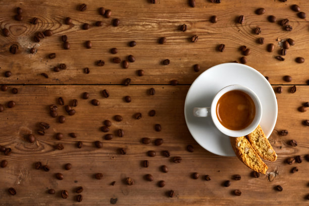 咖啡豆放在杯子里，洒了种子，饼干放在碟子里，放在桌子上图片下载