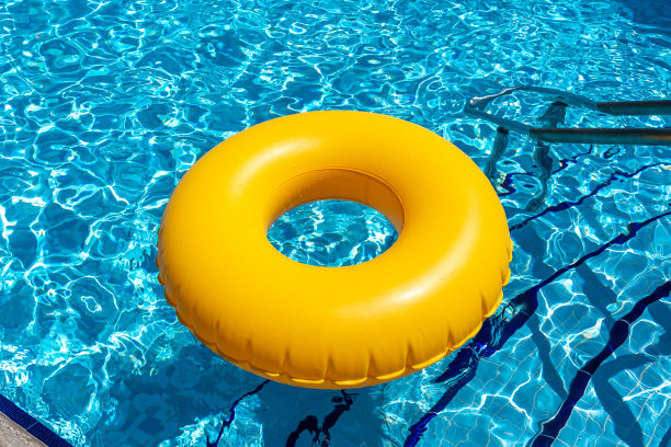 黄色的戒指漂浮在蓝色的游泳池里。充气环，休息概念图片下载