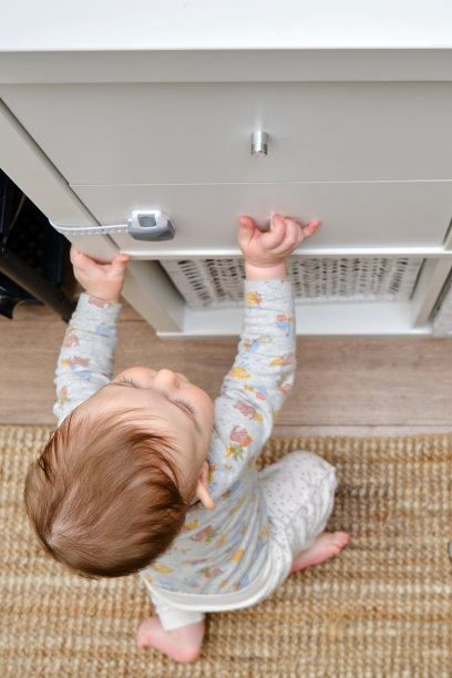 蹒跚学步的小男孩用手扯掉了一个橱柜抽屉。小孩拿着橱柜的门把手，小孩图片下载