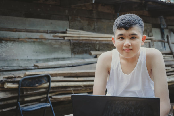 一个男生用笔记本电脑在线学习，直到他的眼睛看到了摄像头。农村家庭远程教育在线学习互联网，教育设备匮乏图片下载