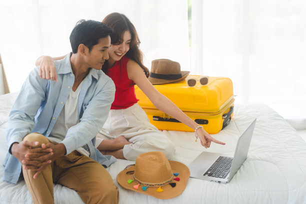 年轻的成年东南亚夫妇使用笔记本电脑准备度假旅行在家里的卧室。图片下载