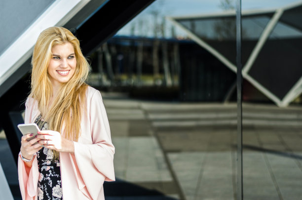 快乐的金发女郎在户外用手机图片下载