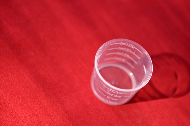 红色背景的塑料量杯图片下载