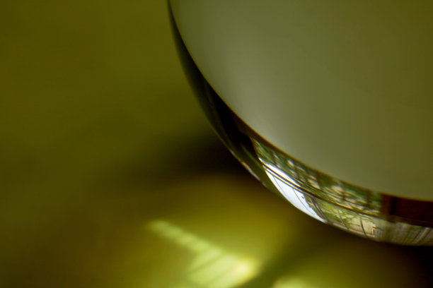 黄色背景上玻璃镜头球的特写图片下载