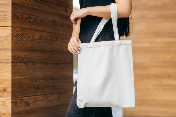 年轻的亚洲模特女孩穿着t恤在街上拿着白色的环保袋，模拟图片下载