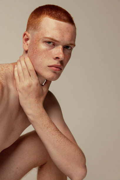 年轻英俊的红发男子在灰色的工作室背景上赤裸上身的肖像图片下载