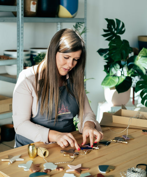 穿围裙的快乐女人在她的工作室里制作零浪费的粘土圣诞饰品图片下载