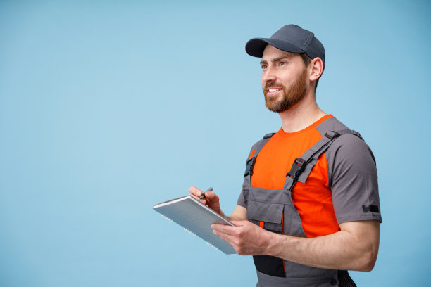 穿着制服的男快递员微笑着看着旁边，手里拿着平板电脑，做着工作笔记图片下载