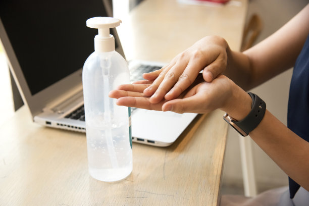 一名妇女在工作时用酒精凝胶洗手，以防止感染covid - 19图片下载