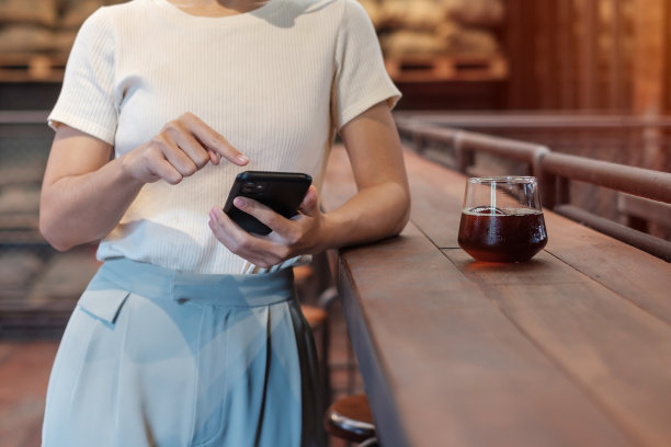 休闲商务女性手持和使用智能手机短信，年轻女性打字触摸屏手机在咖啡馆或现代办公室。生活方式，技术，社交媒体和网络概念图片下载