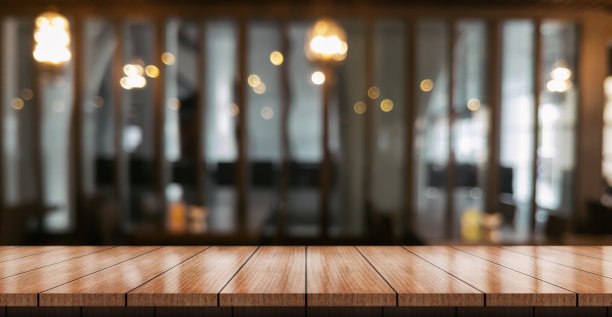空的木制桌面与灯光散焦模糊的餐厅背景图片下载