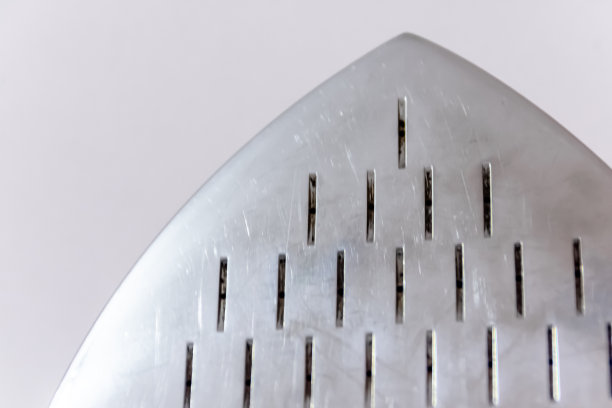 金属银色表面从铁蒸笼洞创造一个独特的图案在干净的白色墙壁背景图片下载