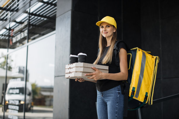 送披萨和热咖啡的快递。给顾客送餐的年轻女孩图片下载