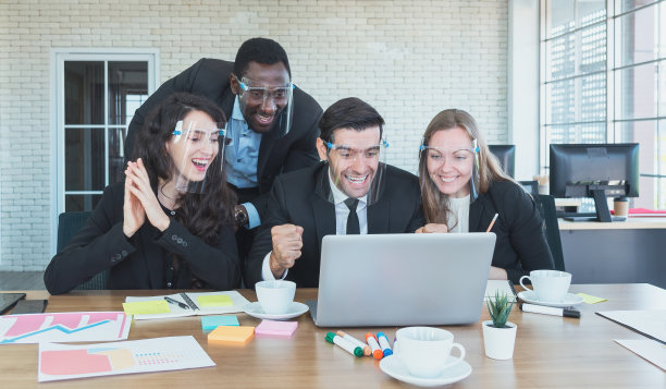 工作时全神贯注。一群年轻的商务人士坐在办公桌前工作和交流，同事坐在后面图片下载