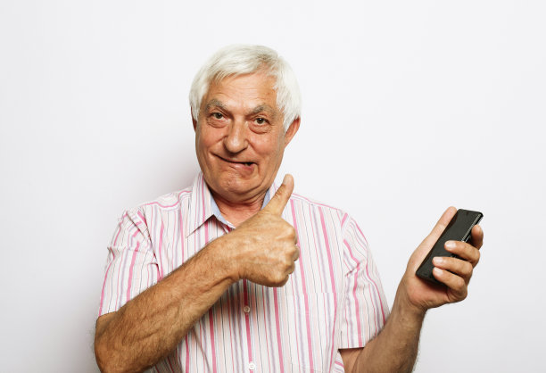 一位穿着条纹衬衫的现代退休老人拿着一部全新的智能手机，展示它。图片下载