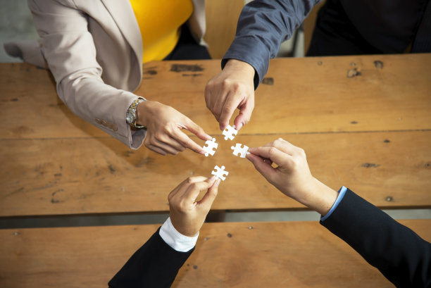 商务人士手中握着七巧板的经营理念图片下载