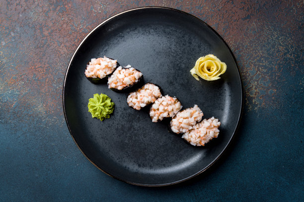 用虾贡观，虾寿司贡观放在黑色的盘子上，在蓝色的混凝土桌面上俯瞰图片下载