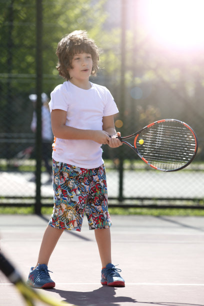 快乐的男孩和朋友在户外打网球图片下载