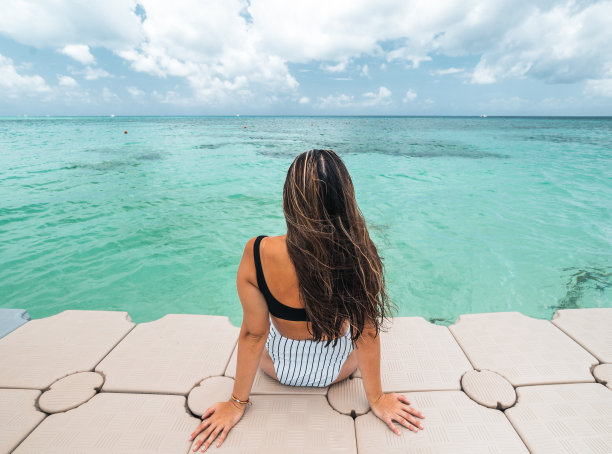 墨西哥科苏梅尔，背朝加勒比海坐着的西班牙妇女图片下载