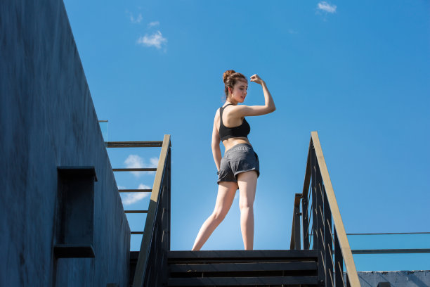 一个阳光明媚的夏日，年轻女子在城市建筑上锻炼- stock photo图片下载