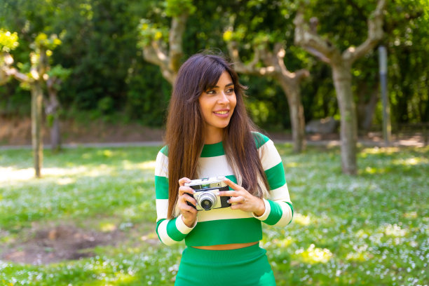 一个深色头发的白人女孩的肖像享受着大自然的纯净空气与相机拍照图片下载
