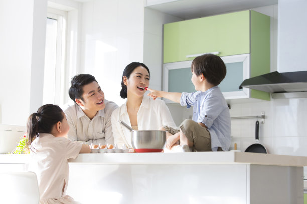 家庭厨房的血统。一家四口一起在厨房做饭，儿子对着他的母亲发出嘘声。- - -库存图片图片下载