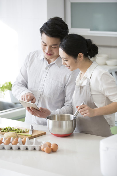 在家里的厨房里，一对年轻夫妇喜欢一起做饭，用平板电脑查看未来购买的商品——库存照片图片下载