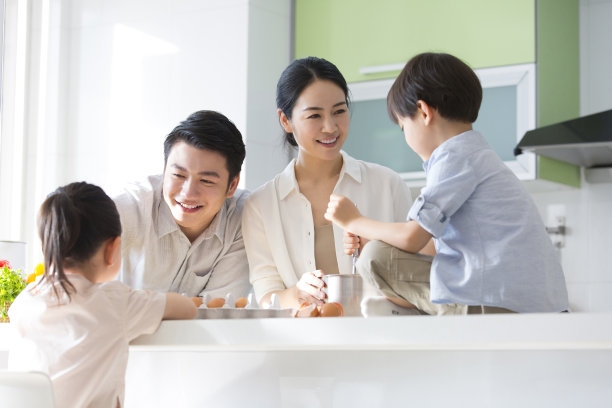 家庭厨房的血统。年轻的父母很乐意看他们的儿子和女儿玩耍。- - -库存图片图片下载