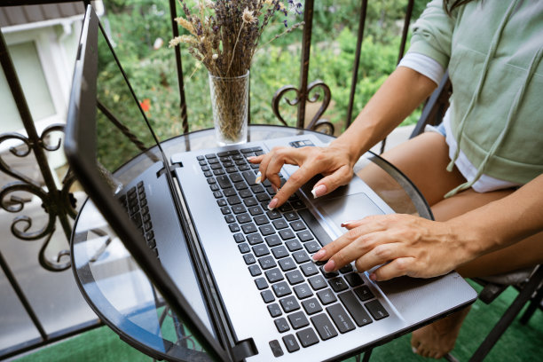 年轻女子在阳台上用笔记本电脑工作图片下载