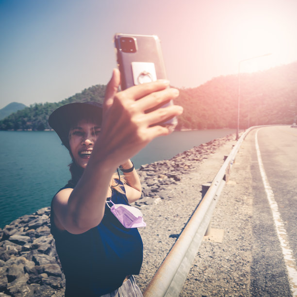 一名身着夏日礼服的亚洲女子在美丽的沙滩上用手机自拍。图片下载