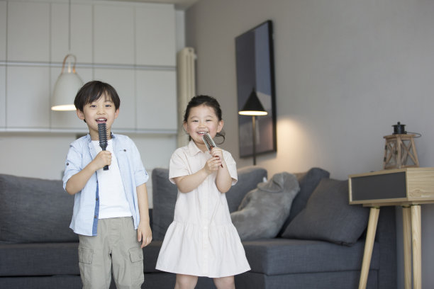 一个小女孩和一个小男孩在客厅用梳子当麦克风唱歌-库存照片图片下载