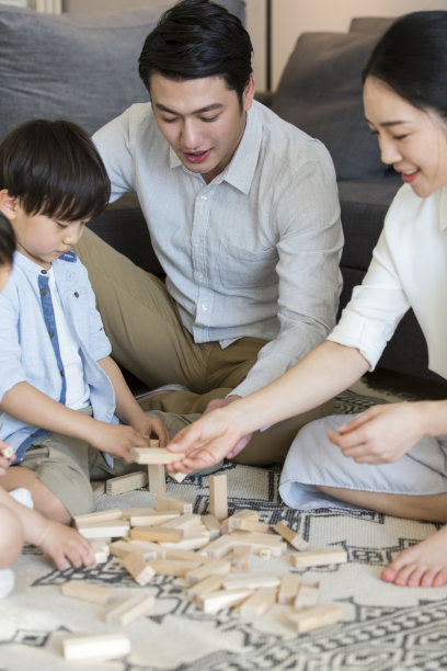 一对父母陪着他们的两个儿子和女儿在客厅的地毯上玩积木——照片图片下载